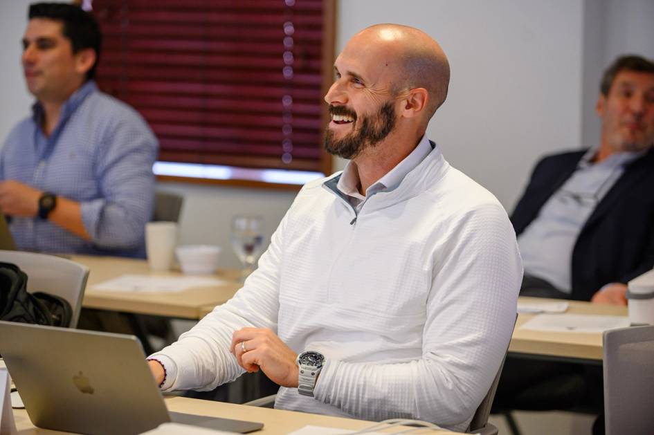 Smiling professional participates in meeting while working on laptop at desk