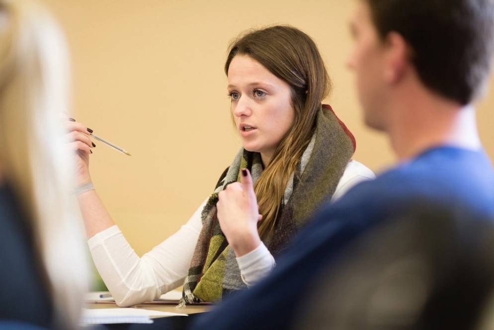 A student at her desk speaking to professor Kozel.