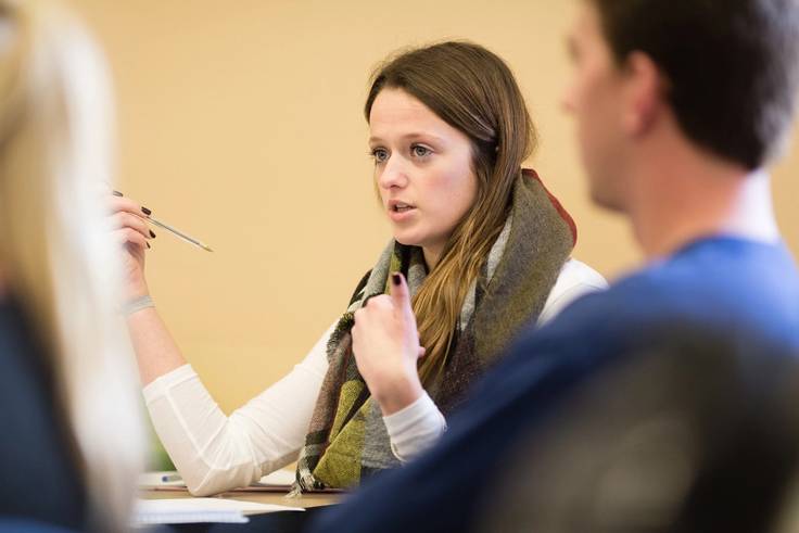 A student at her desk speaking to professor Kozel.