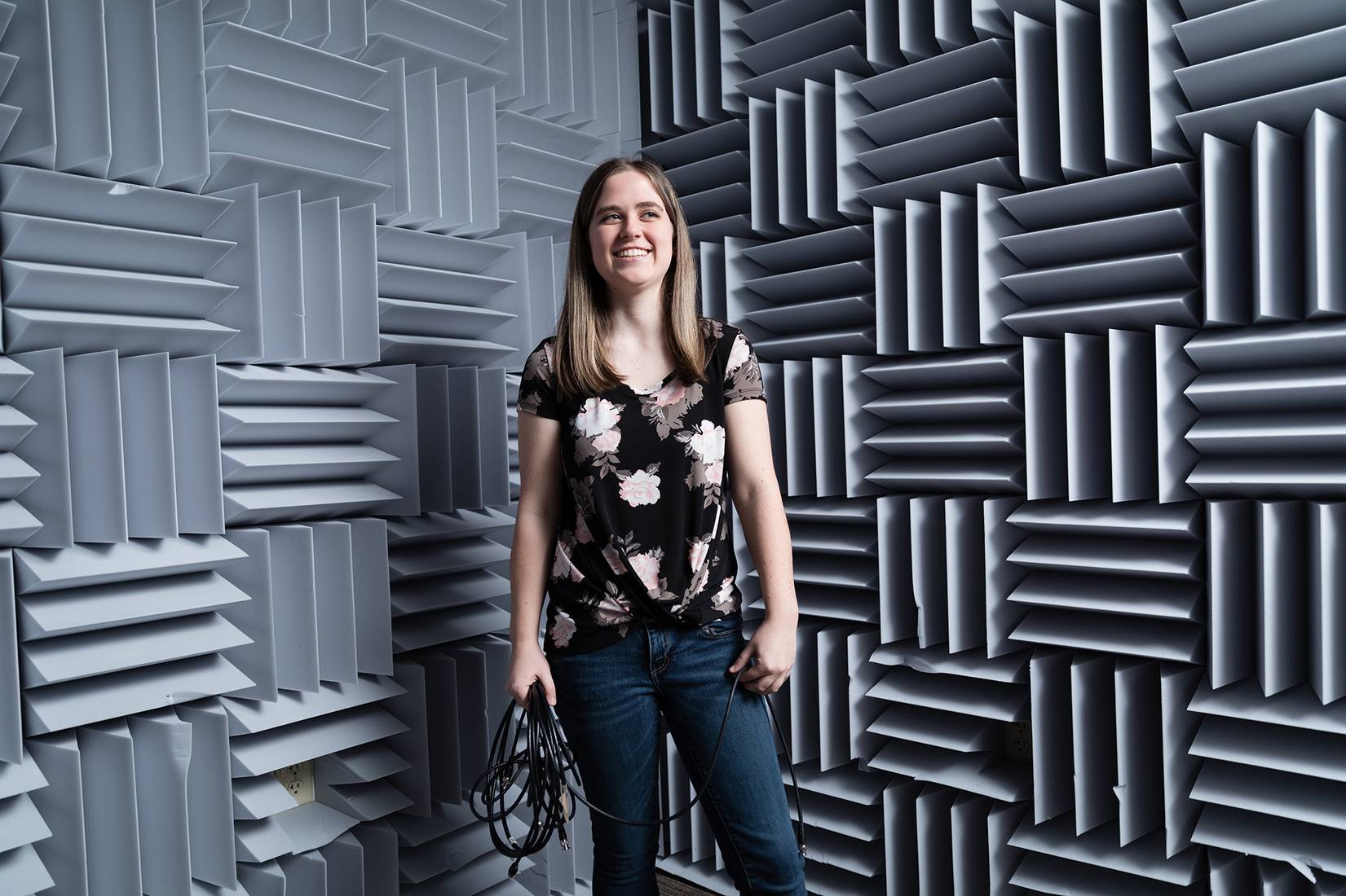 Lauren Neldner in an acoustic room holding cables.