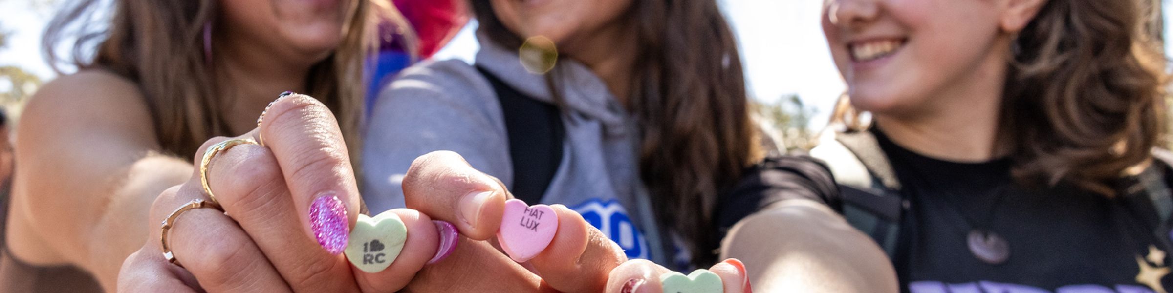 Three female students holding candy hearts.