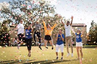 Students celebrate on Mills Lawn with confetti.