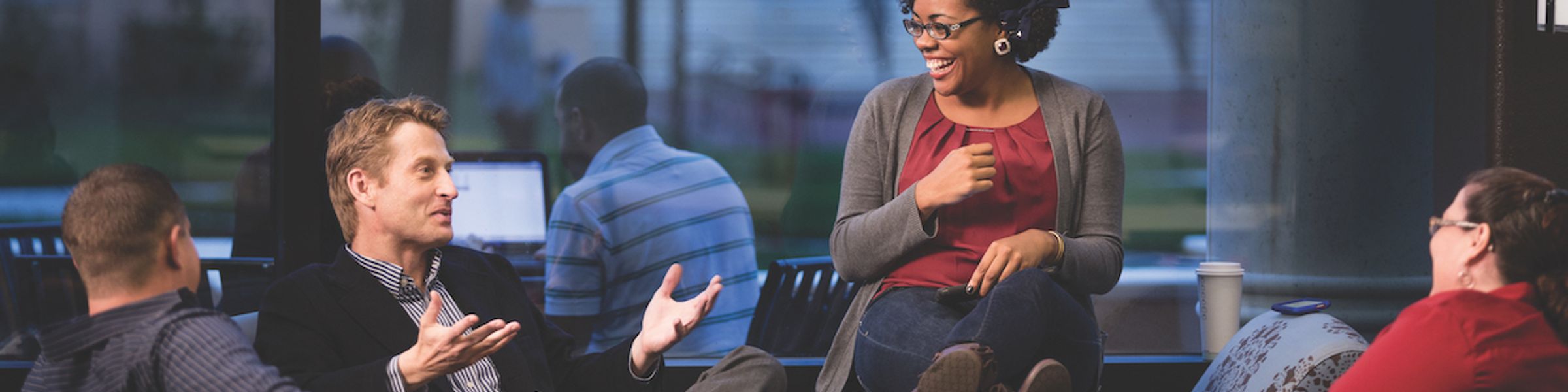 A group of adult college students chats during a break from class.