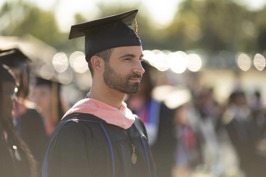 Graduate in cap and gown, looking accomplished.