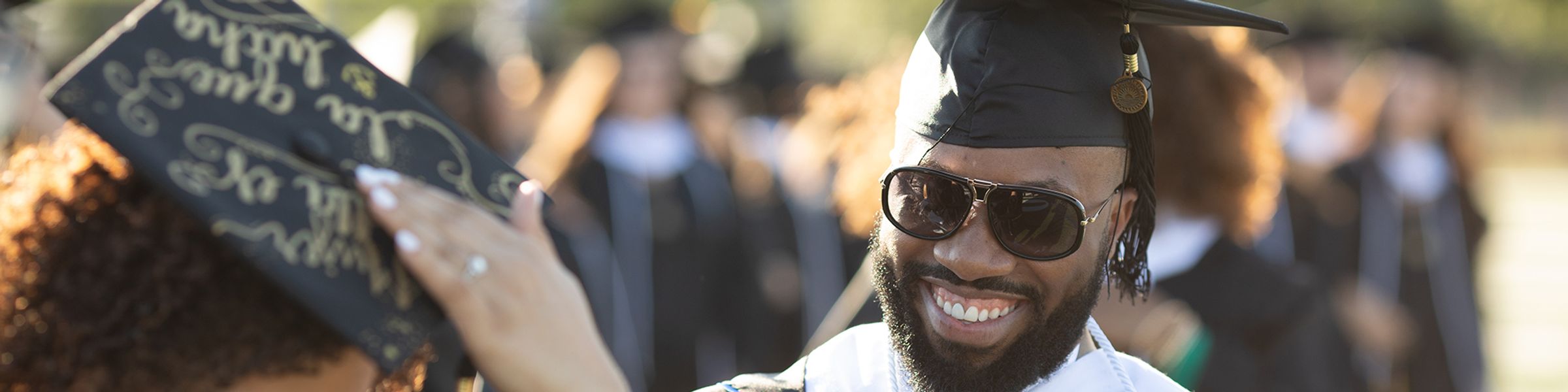 A male college graduate smiles during a commencement ceremony.