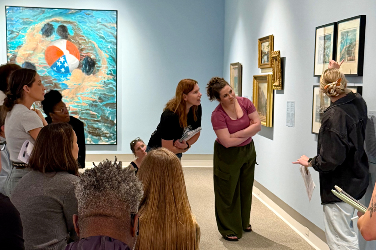 Museum educator leading group discussion in gallery of framed artworks
