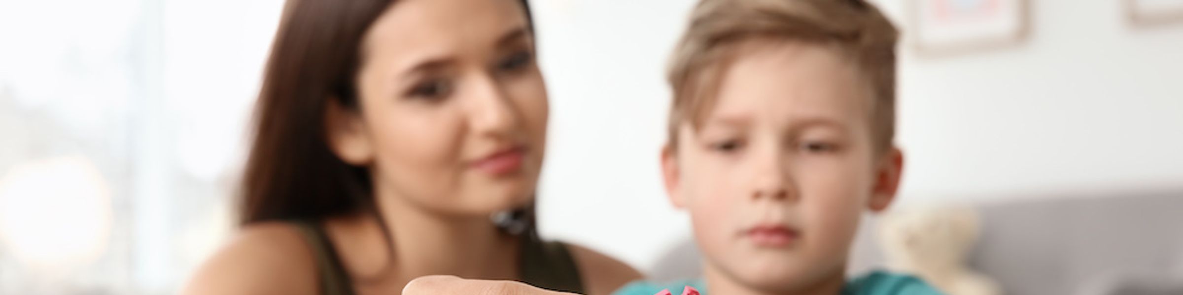 A behavior analyst helps a young patient assemble a colorful foam puzzle.