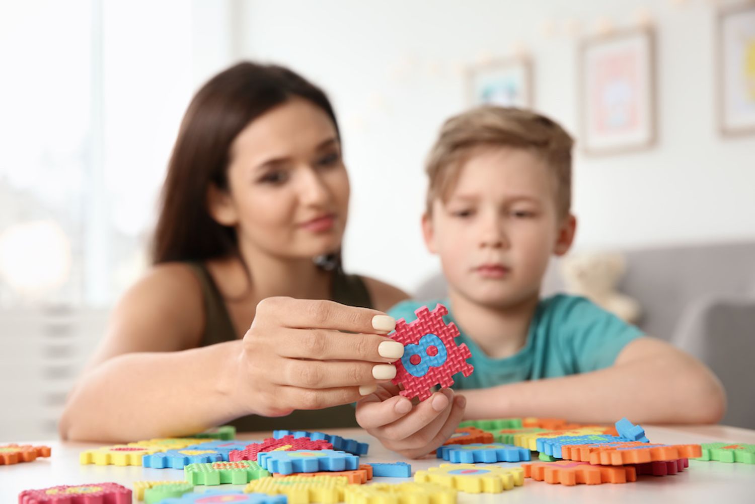 A behavior analysts works with a student using brightly colored puzzle pieces.