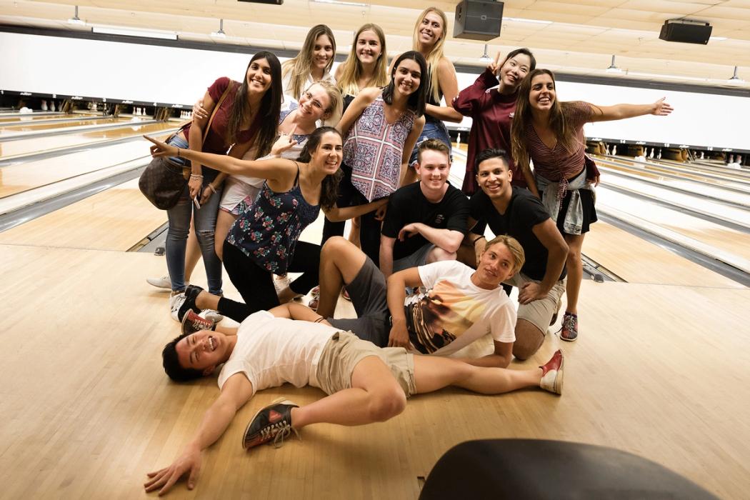 A group of Rollins College students pose for pictures at a bowling alley.