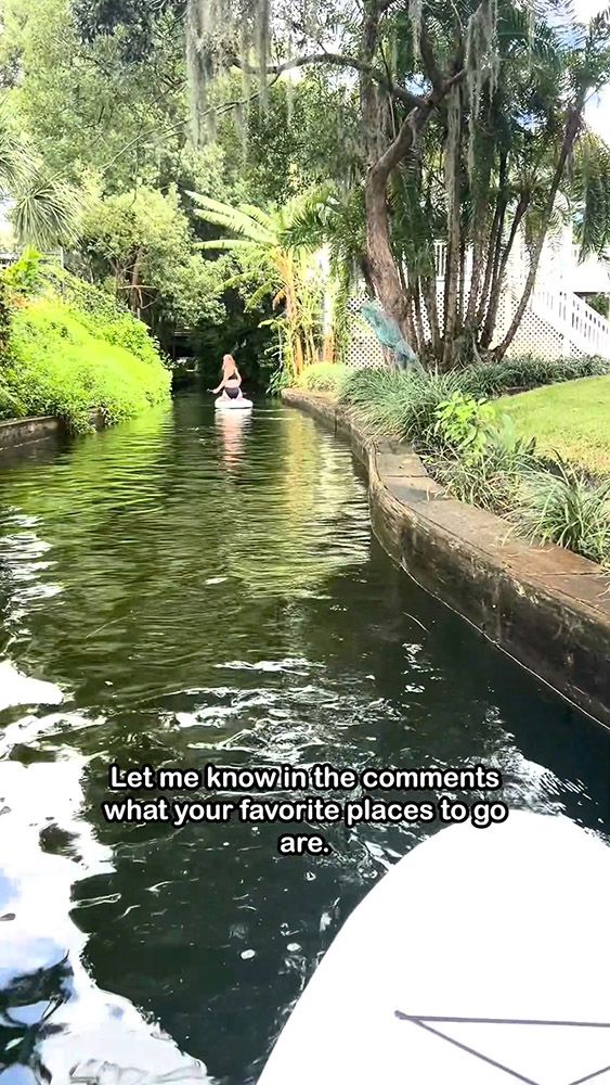 Person paddleboarding through narrow, lush canal with text overlayed about travel.