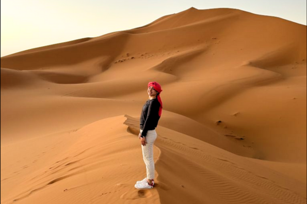 Rollins student in Morocco standing on sand dunes