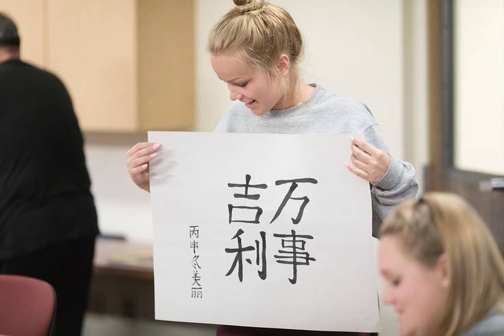 A student posing with their calligraphy.
