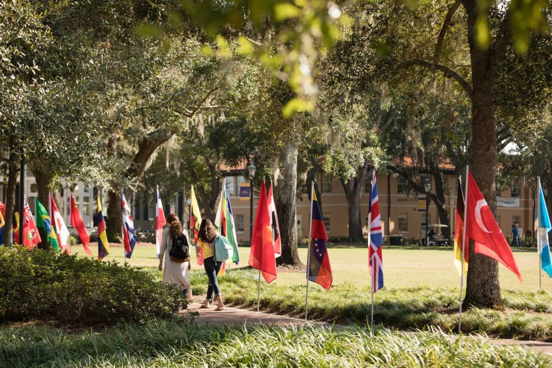 multiple country's flags displayed around Mills Lawn, while two students walk along the path