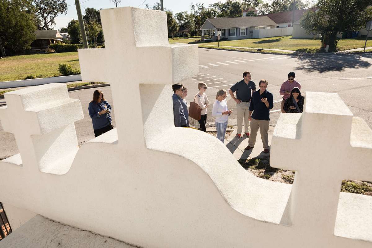 Students standing on a street corner behind three white crosses of a local church.