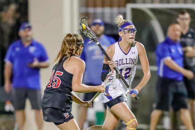 A female lacrosse player running past a defender during a game.