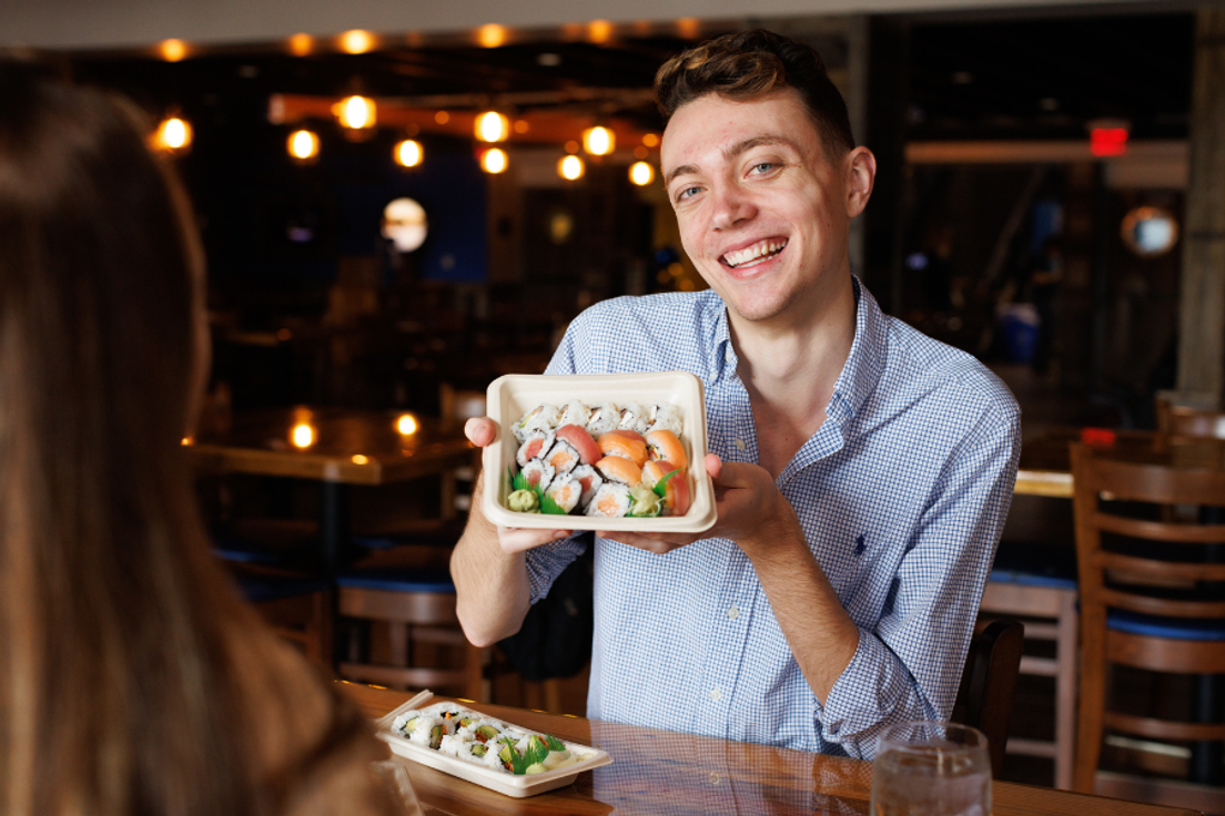 Rollins student Brendan Manning '23 holding up sushi box