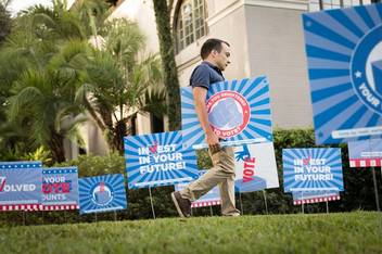 A student places voting signs on campus.