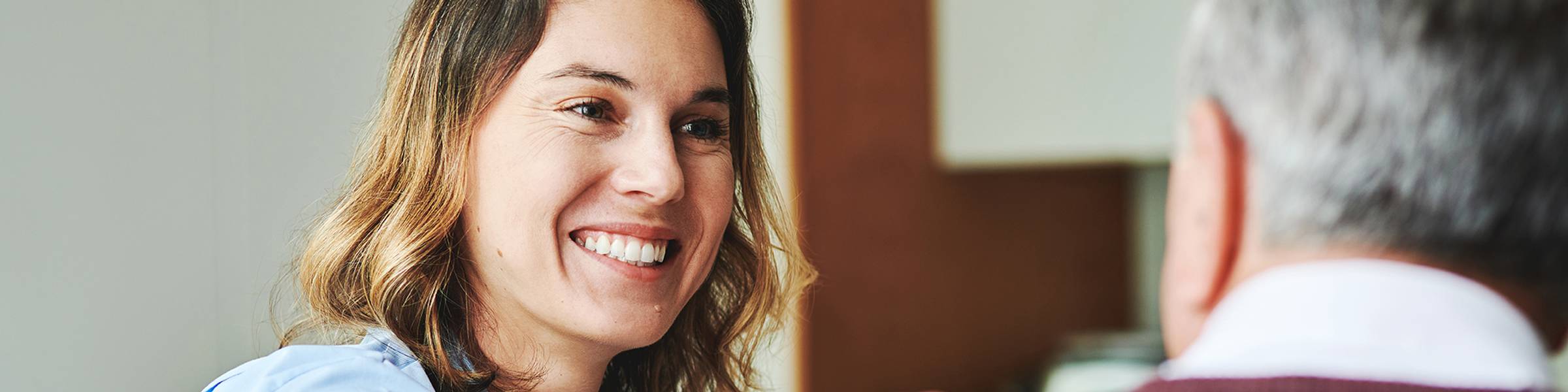 A community health workers places her hand on an elderly man's shoulder.