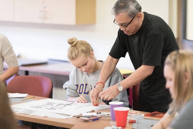 A Rollins professor helps a student in a calligraphy class.