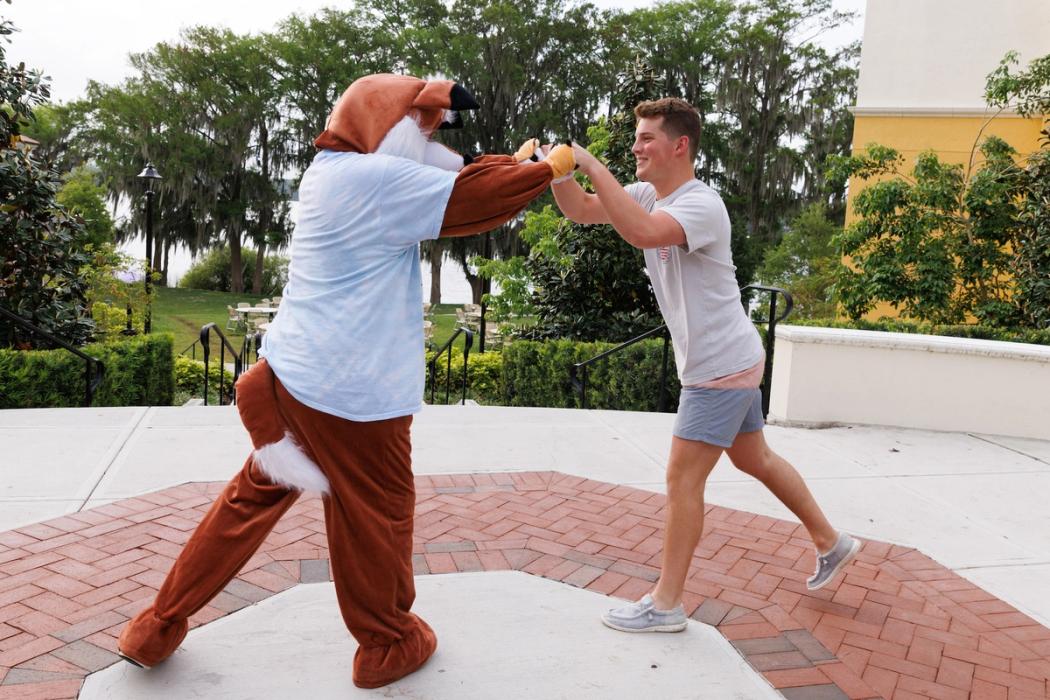 A student and the Rollins College fox fist bump.