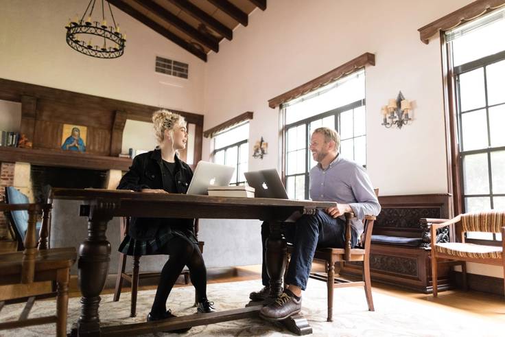 A religious studies professor and student work together on laptops.