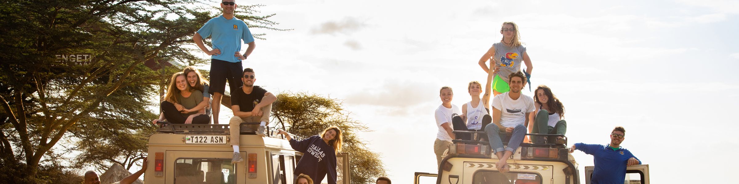 A group Rollins College students pose with safari trucks on a study abroad trip in Kenya.