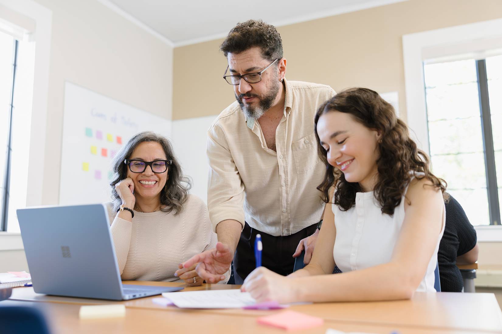 A counseling professor works with two students in a classroom
