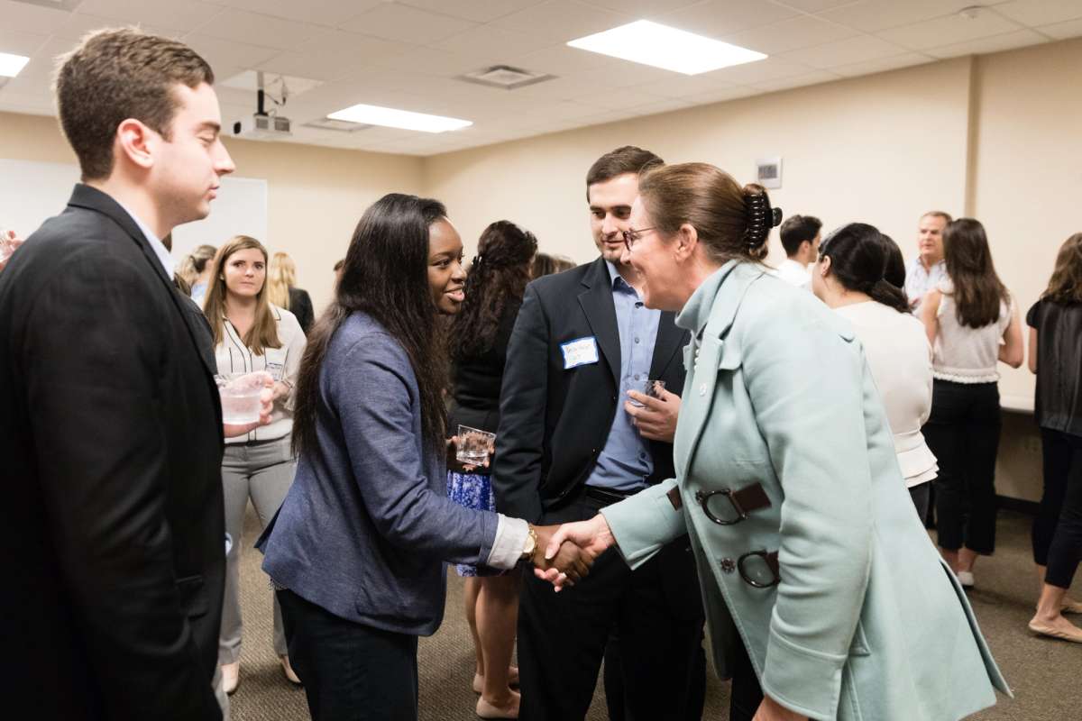 A student shaking the hand of a business owner.