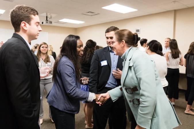 A student shaking the hand of a business owner.