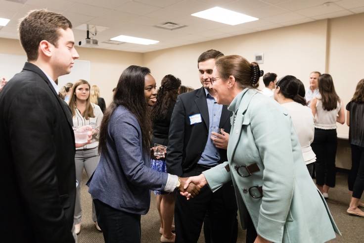 Students shake hands at a networking event. 