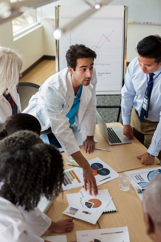 A group of health-care professionals engaged in discussion around a conference table.