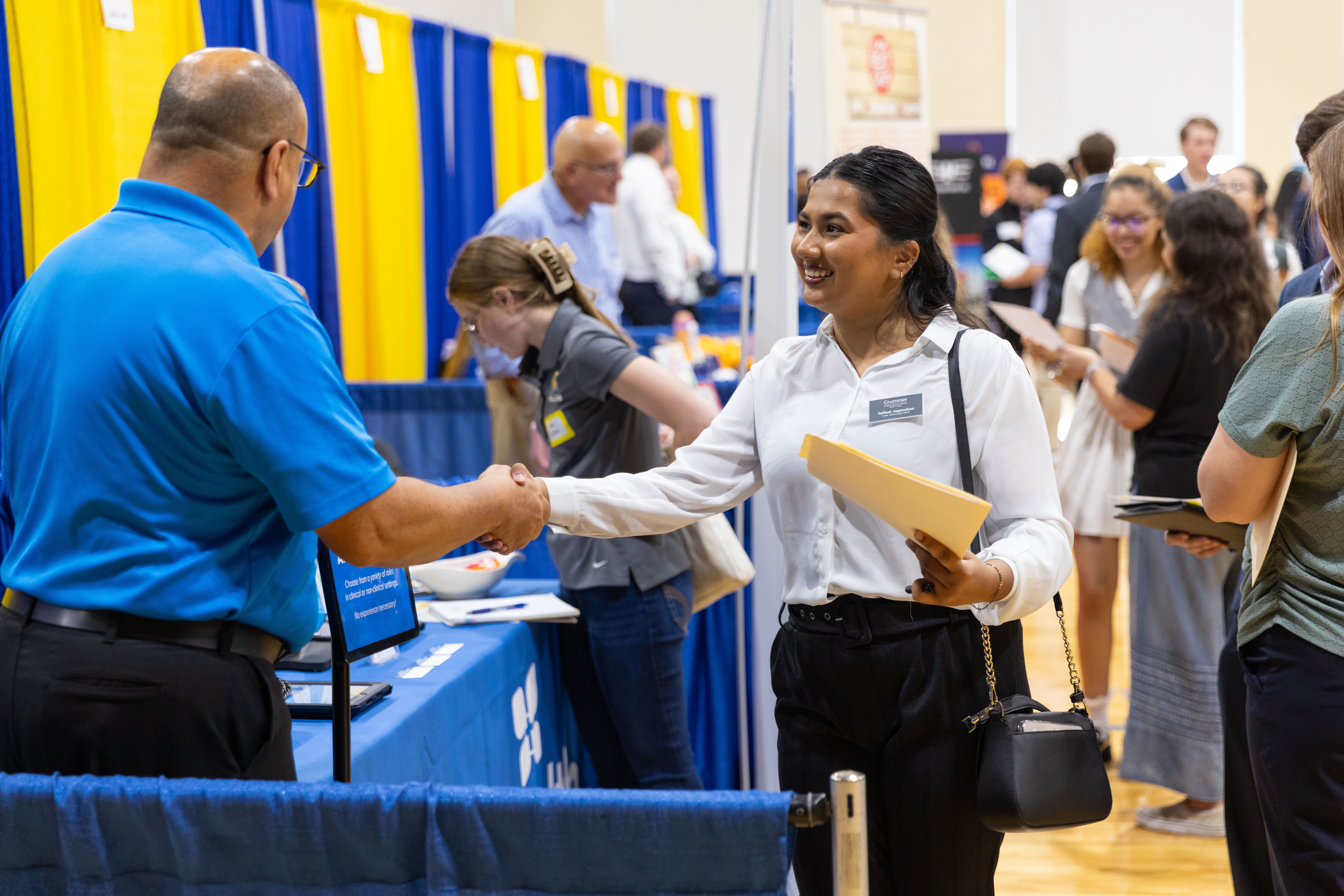 Female student shaking hands with employer at job fair