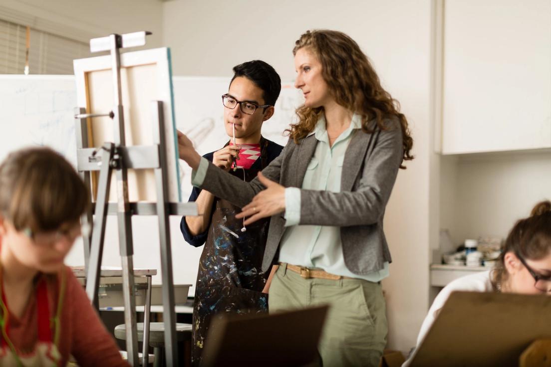 A student and a professor scrutinize a painting