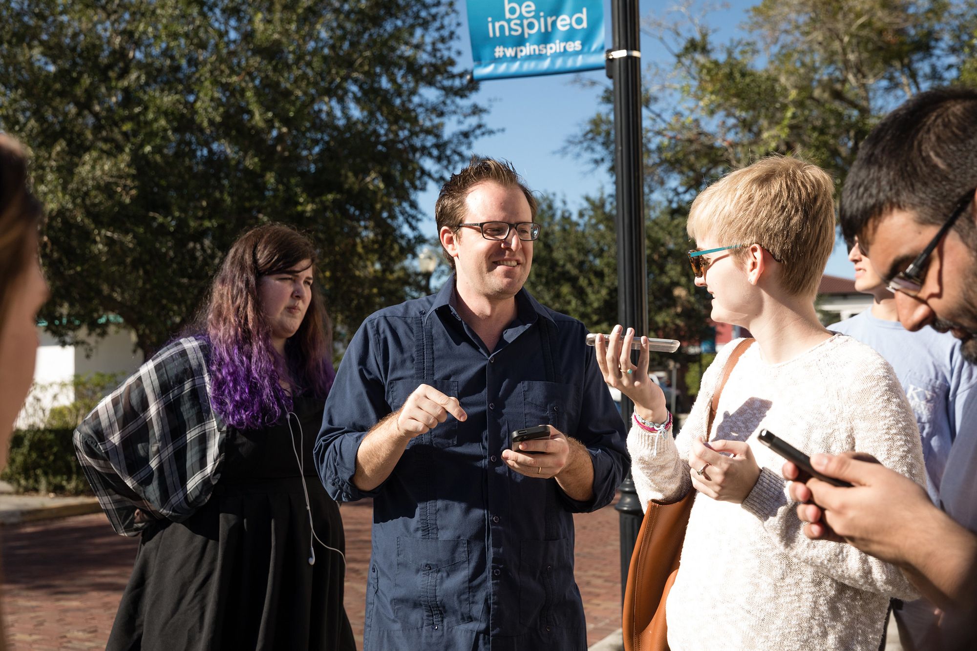 Professor Dan Myers talking to a student as she speaks into her digital device.