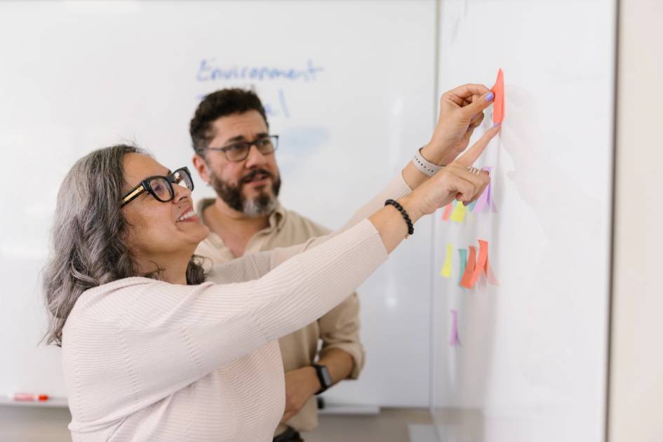 Two adults working on whiteboard. 