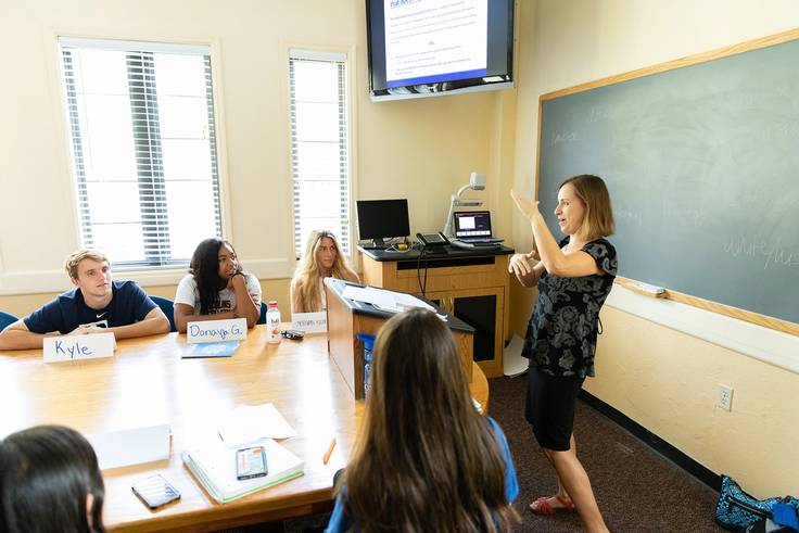 A college professor instructs a small class of students. 
