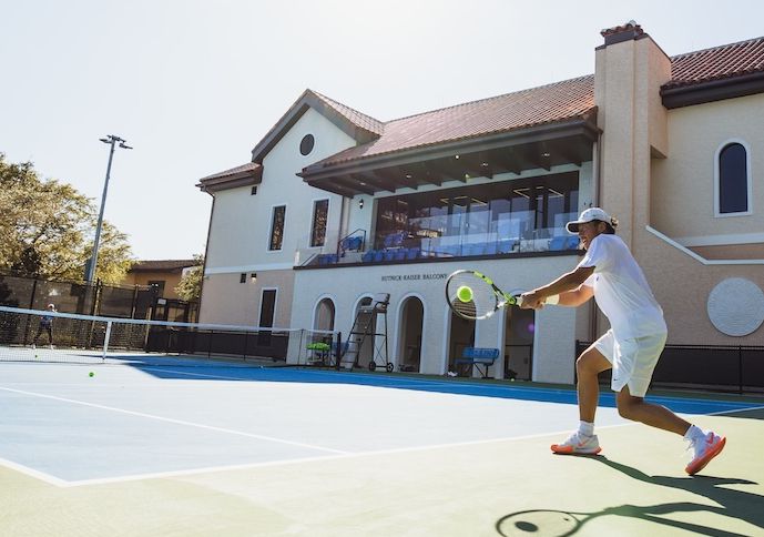 A tennis player returns a shot from the baseline.