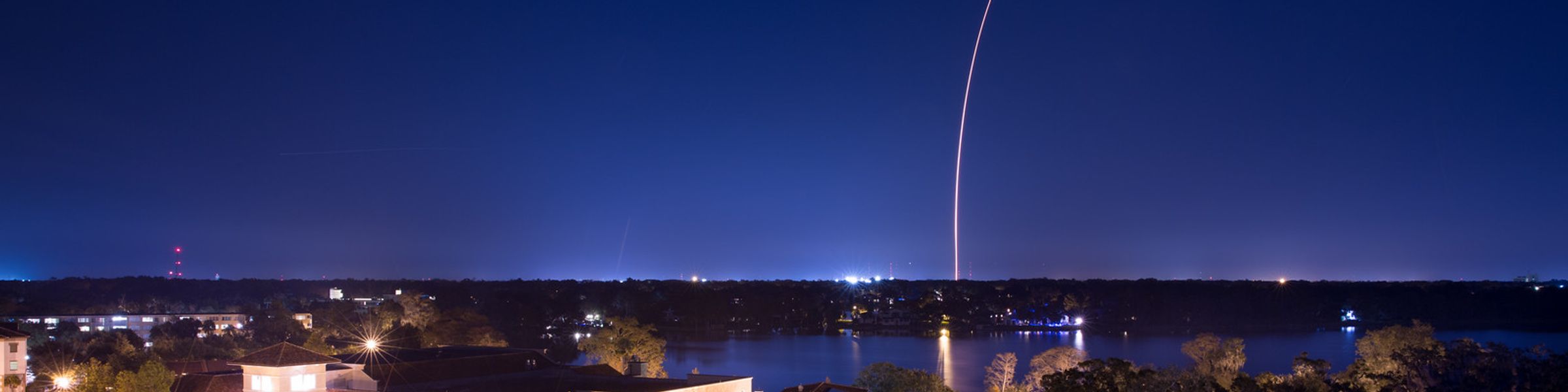 Rollins campus at night with a clear image of a rocket launching in the distance