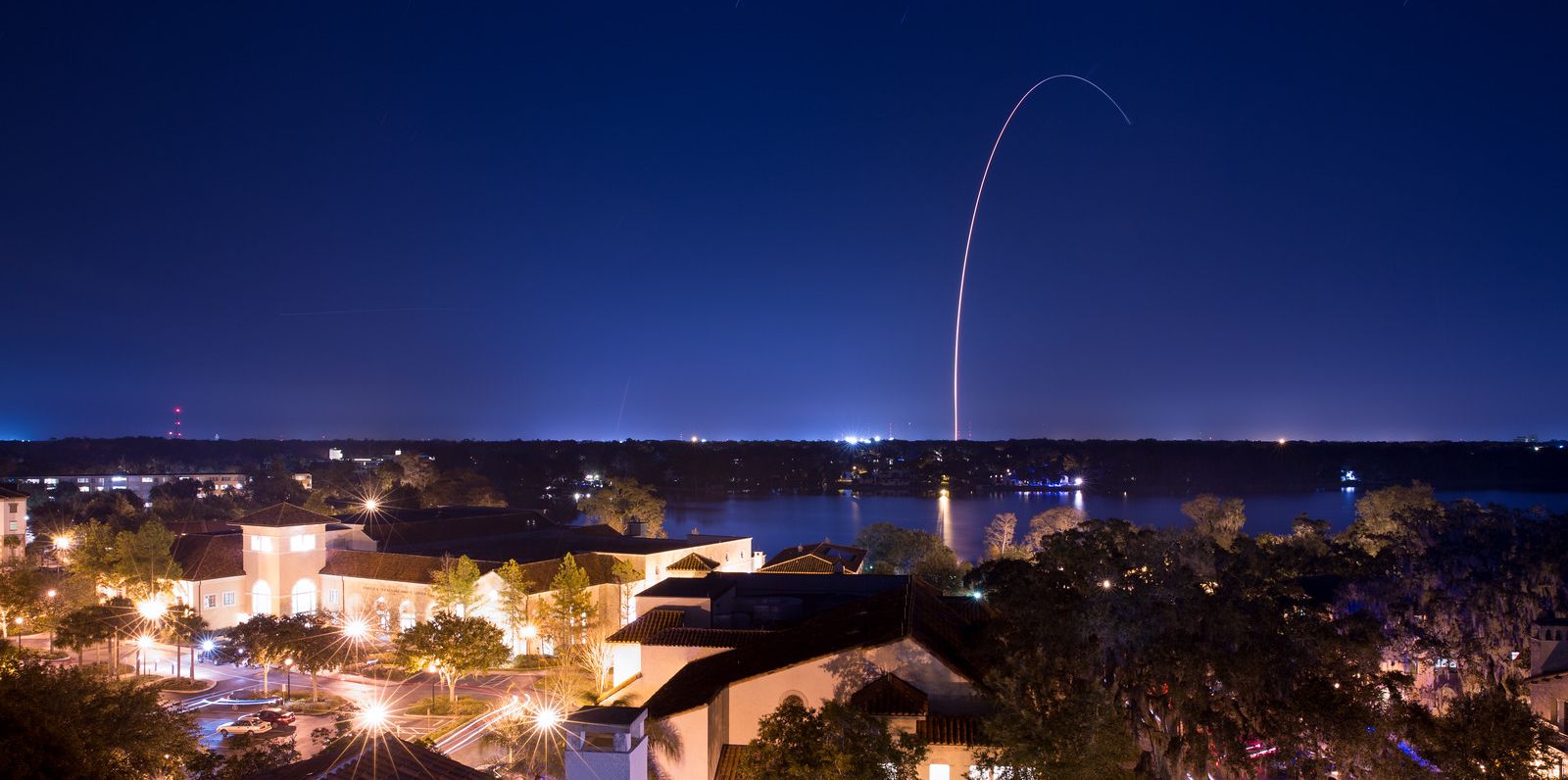 Rollins campus at night with a clear image of a rocket launching in the distance