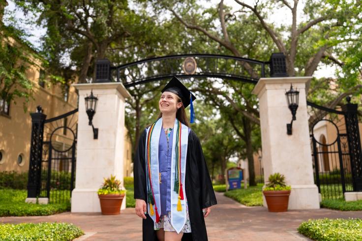 Skylar Hines in graduation regalia on Rollins campus.