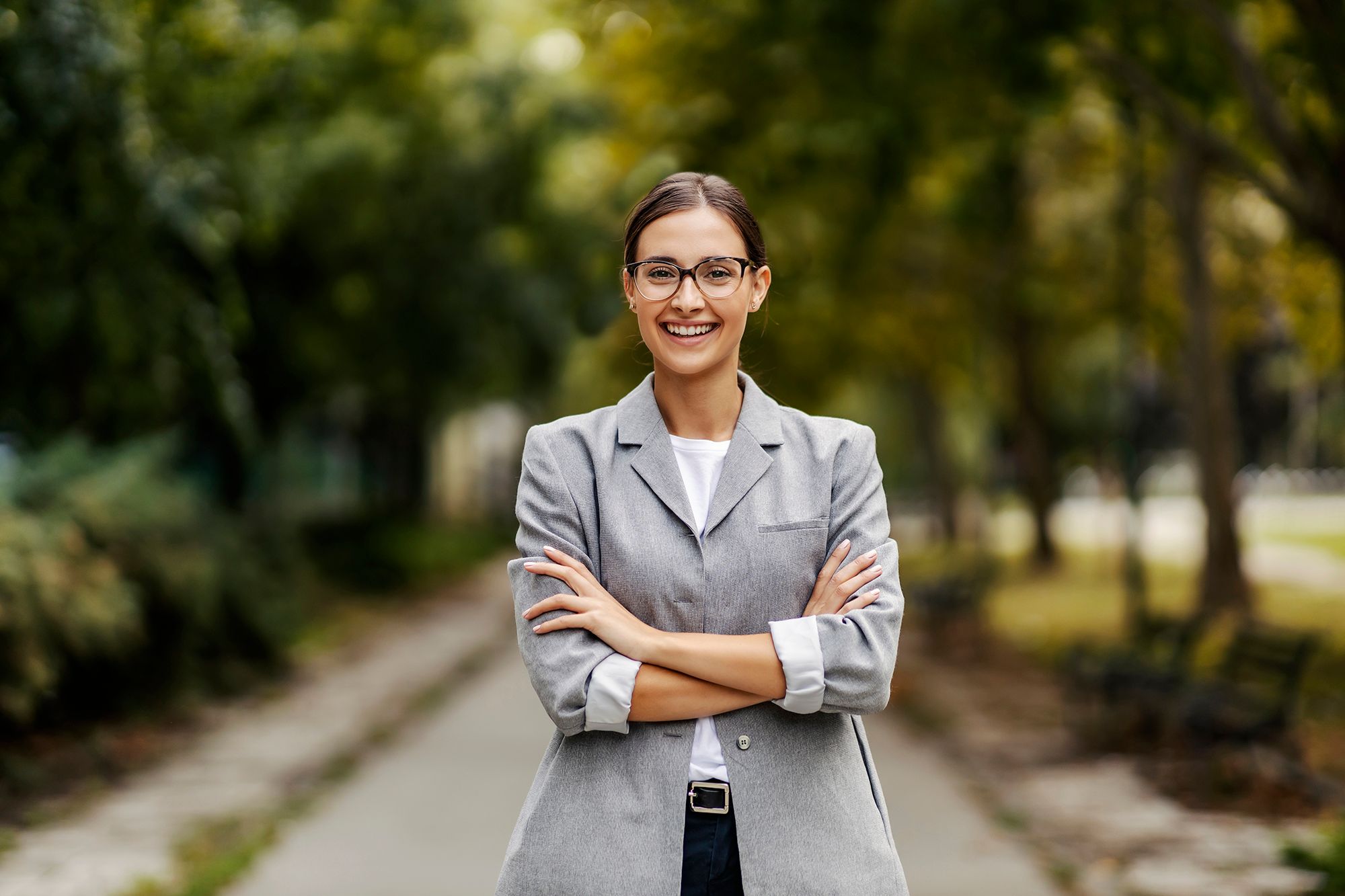 A young professional poses with her arms crossed on a bike path.