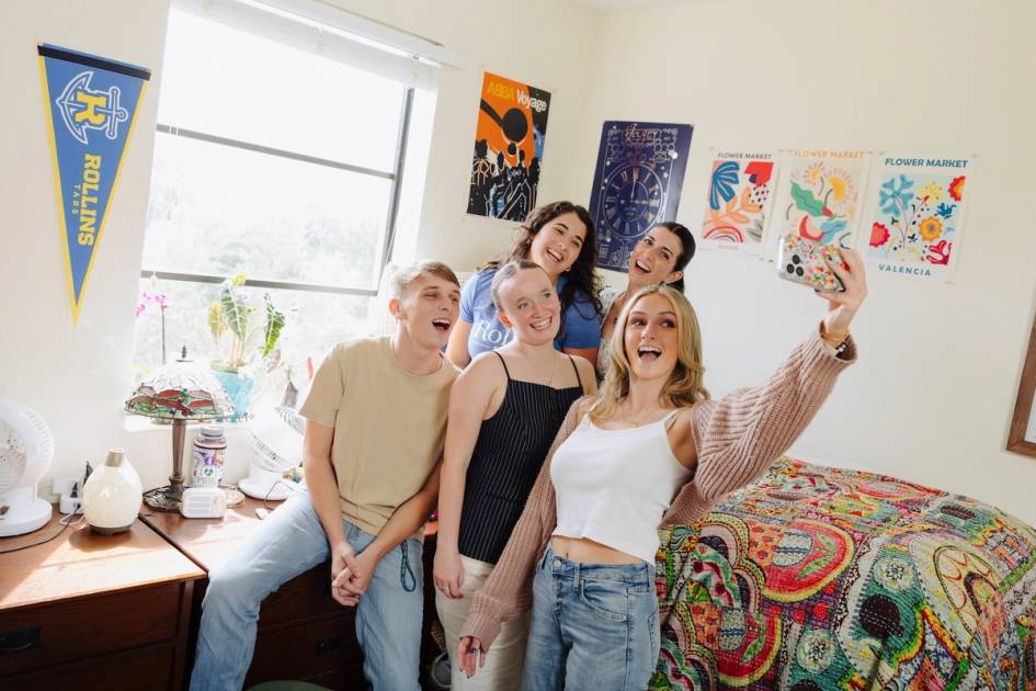 A group of students pose for a selfie in a Rollins dorm room.