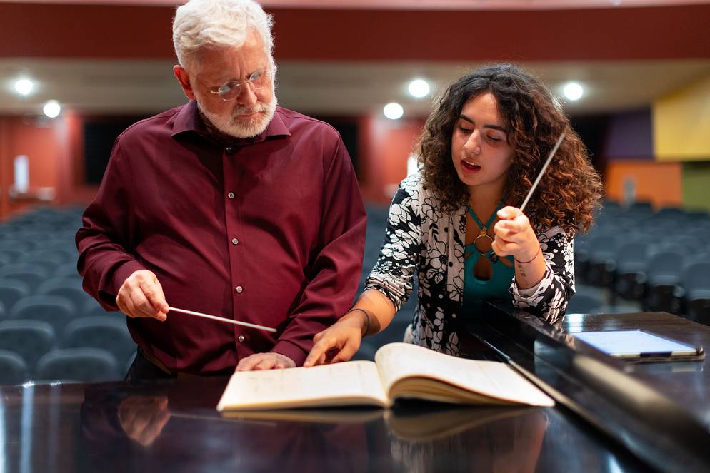 A music student and professor collaborate on a conducting lesson