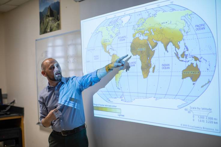 Rollins College professor points to a world map in the classroom.