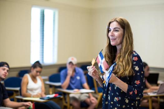 A Spanish professor holds flags of South American countries during a lecture.