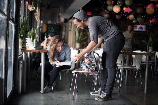 Two college students laughing at an assignment in a local coffee shop.
