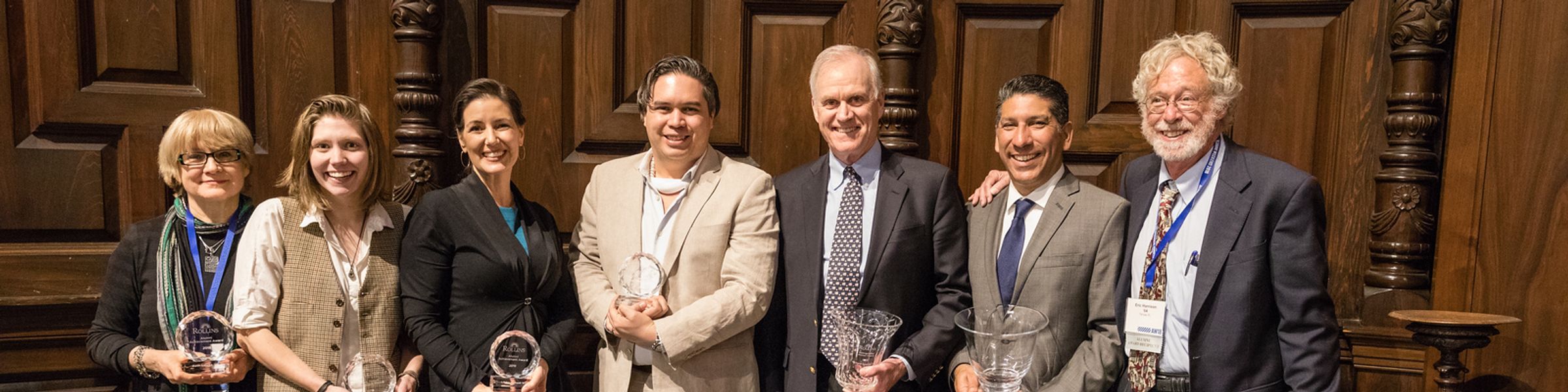 A group of alumni holding a variety of awards.