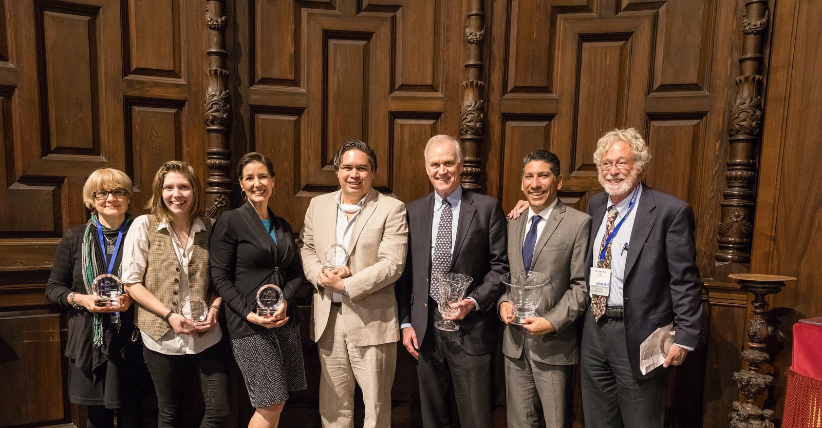 A group of alumni holding a variety of awards.
