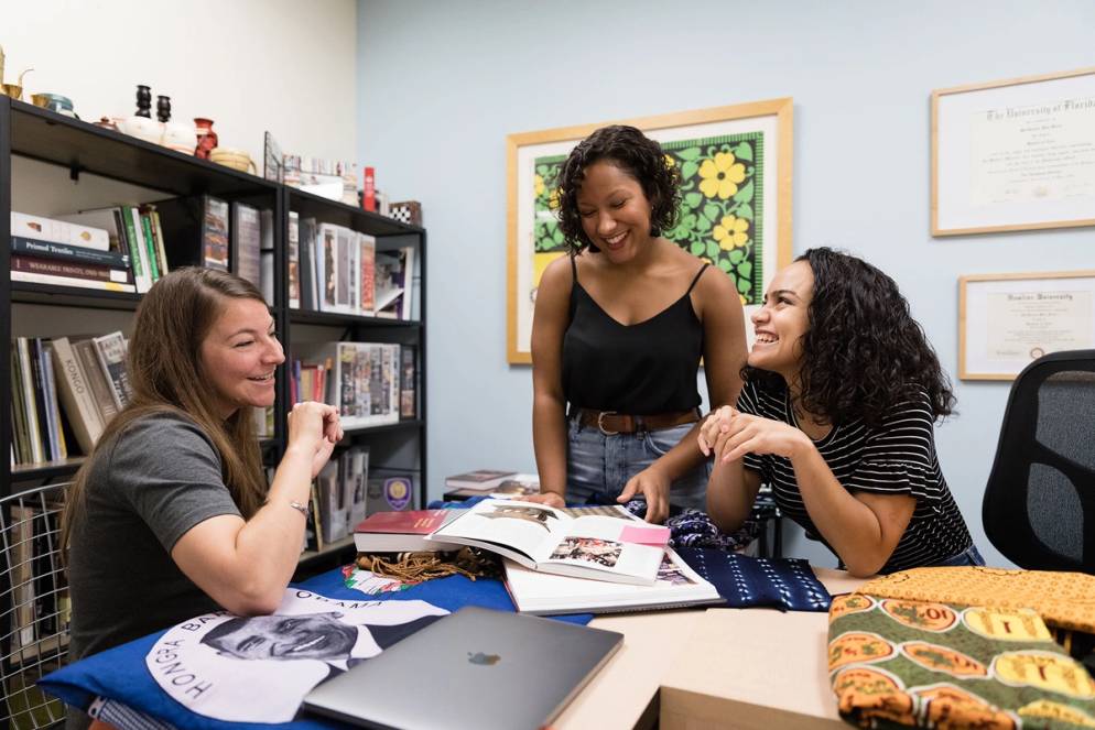 Cristina Toppin, MacKenzie Moon Ryan, and Morgan Snoap examine African artifacts as part of a research project.