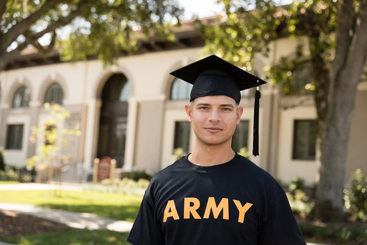 A student veteran poses in an Army shirt and a graduation cap.